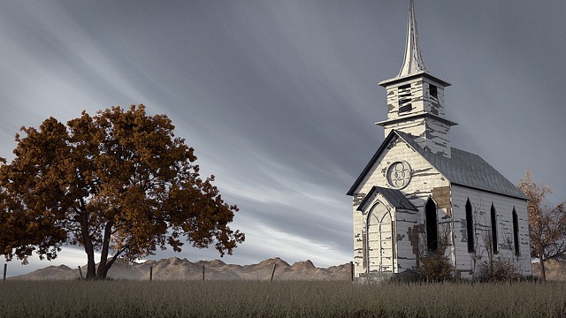 Old abandoned church under a gray sky surrounded by brown leaves and a wire fence symbolizing spooky Halloween superstitions