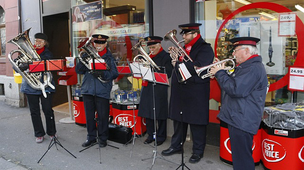The Salvation Army band performing Christmas music on a city street with five members.