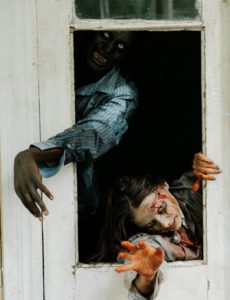 Zombies reaching through a broken door inside a haunted house attraction
