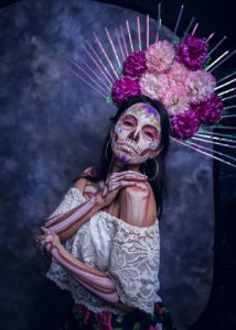 Woman dressed as La Catrina with skull face paint and large flower headdress