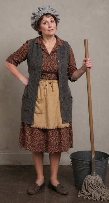 DIY Carol Burnett Cleaning Lady Costume with yellowish apron, sweater vest, mop cap, brown dress, and mop and bucket props
