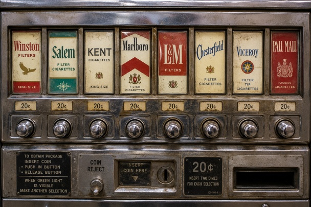 Close-up of a vintage vending machines brand selector panel with worn buttons and coin mechanism