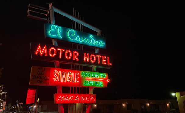 Vintage neon motel sign glowing outside a mid-century motel along an American highway