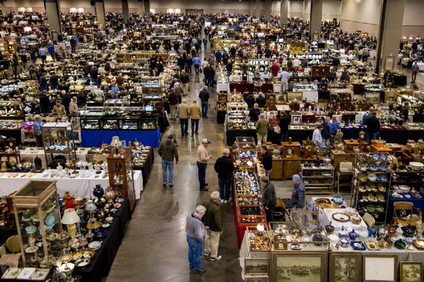Vintage Halloween Collectibles buyers browse vendor booths at a large antique show and collector convention filled with rare seasonal treasures.