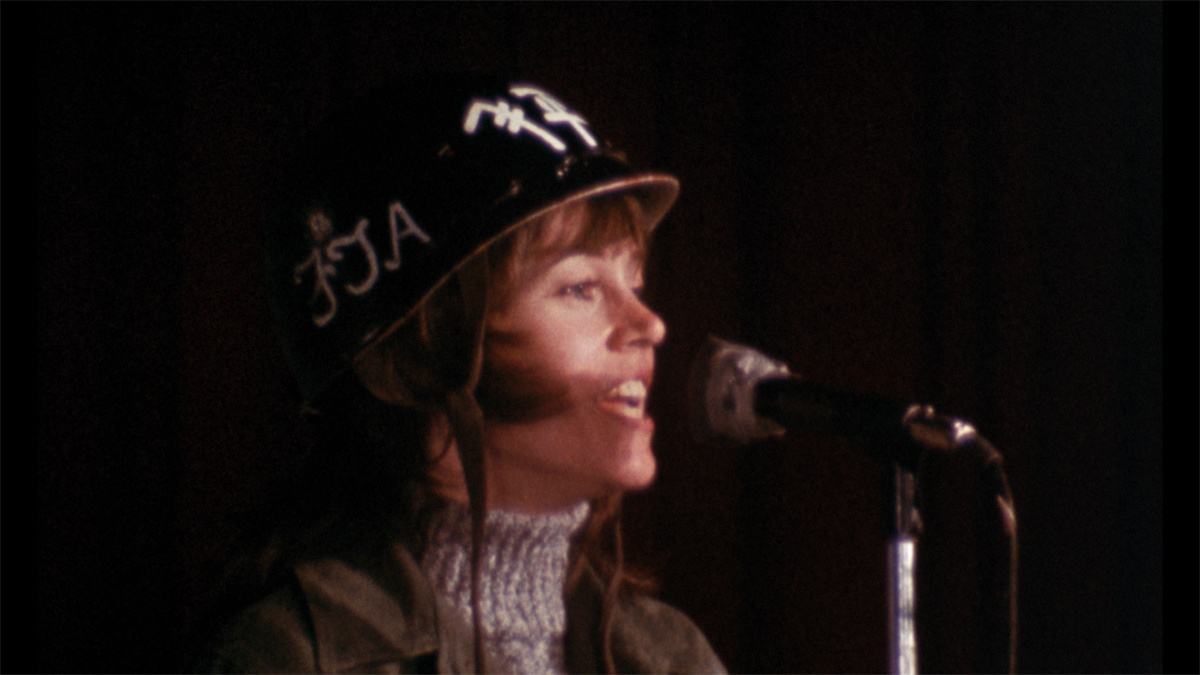 Jane Fonda speaking into a microphone during the anti-war entertainment tour featured in the F.T.A. Review.