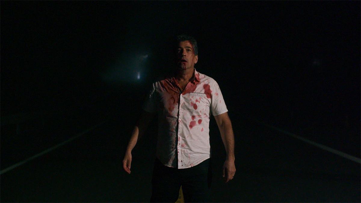 Malicious 2023 Review showing Nick Baillie attempting to escape in a suspenseful scene from the horror thriller.